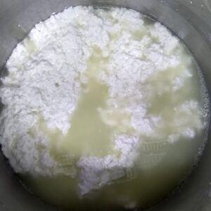 homemade queso fresco in process. A pot full of curds and whey ready for draining.