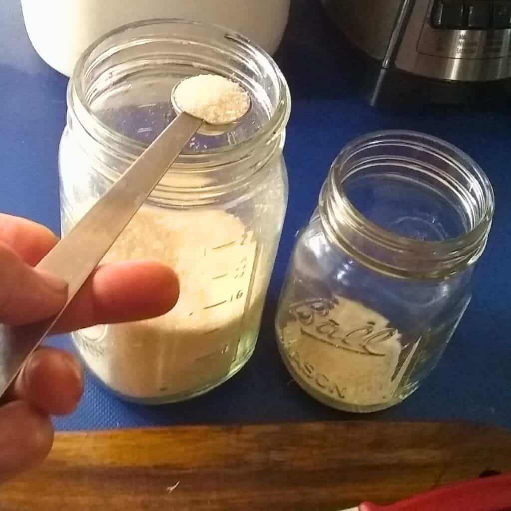 Adding sugar to the pint jar to make the ginger bug recipe from scratch
