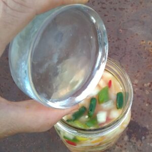 A fermentation weight being placed onto the hot sauce ingredients.