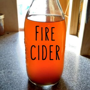 bottle of fire cider in front of a window