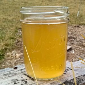 a glass full of homemade switchel on a pallet in the garden