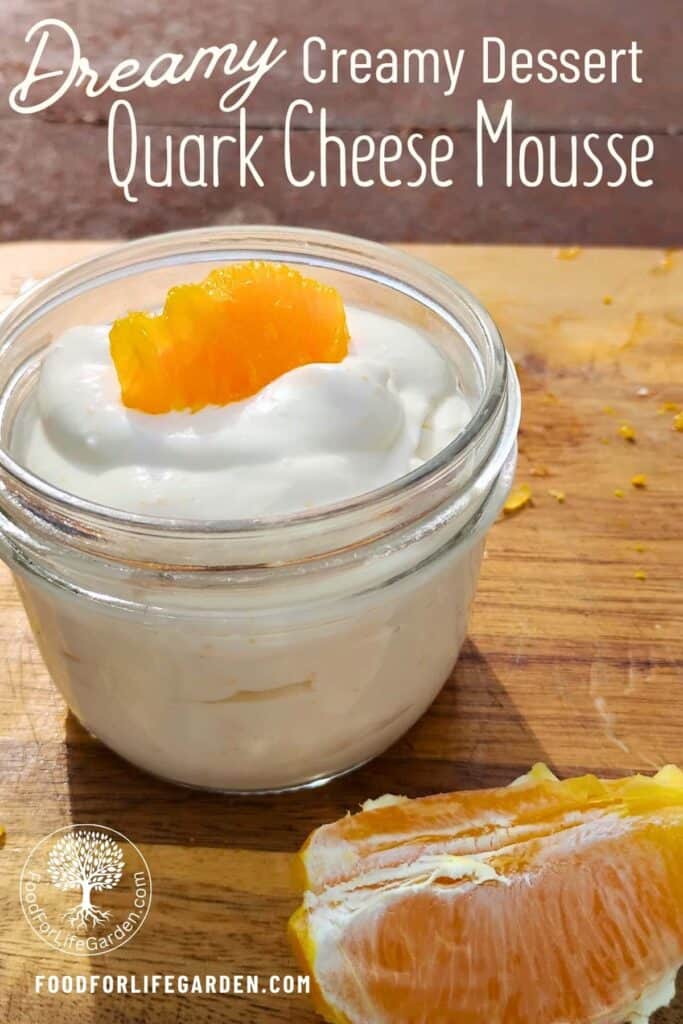 bowl with finished quark cheese dessert and an orange slice for decoration. A piece of orange is in front of it. text overlay reads dreamy, creamy dessert, quark cheese mousse. foodforlifegarden.com.