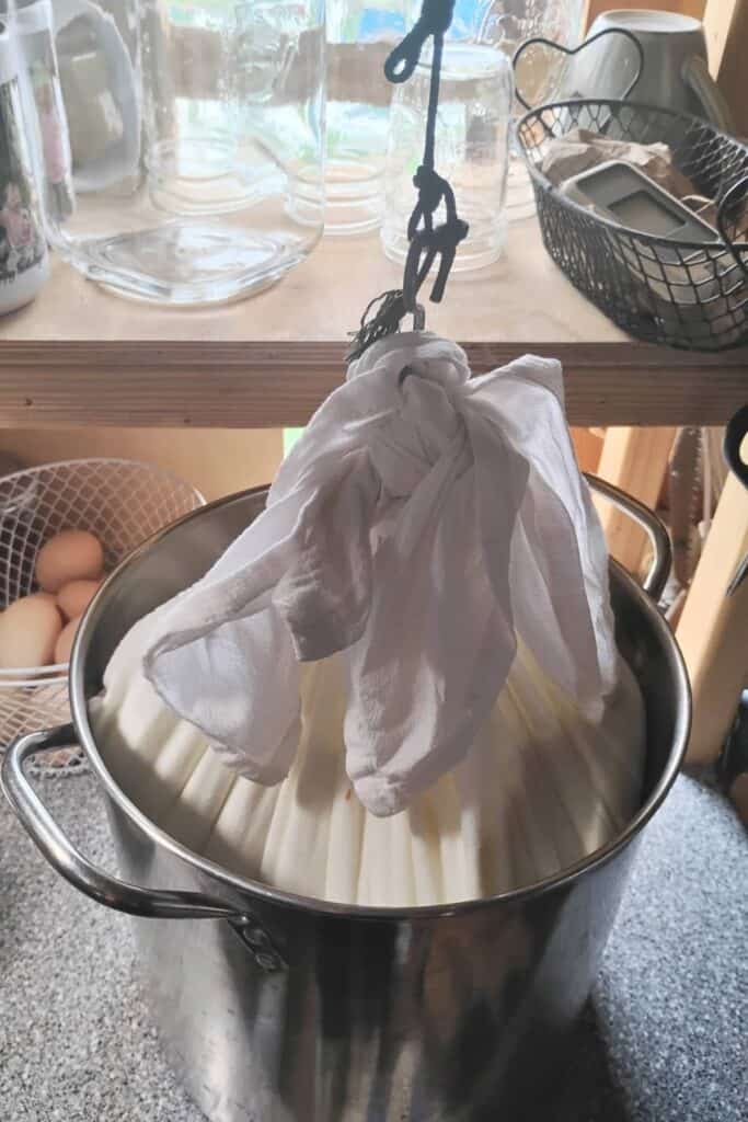 a bag of quark cheese curds hanging from a hook and dripping into a pot.