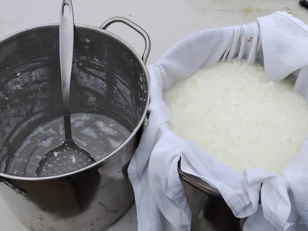 an empty cheese making pot and a full cloth lined pot with cheese curds