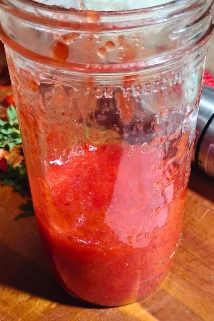 pureed strawberries in a glass mason jar.
