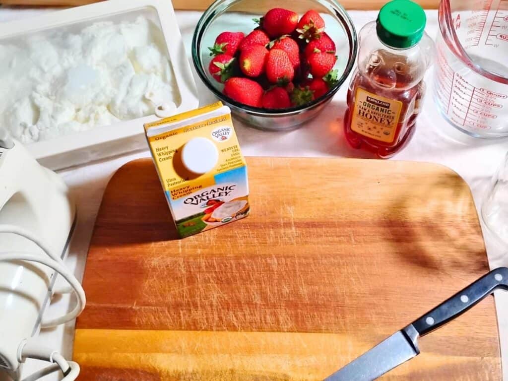 ingredients for making strawberry quark cheese mousse. Quark, strawberries, honey and whipping cream.