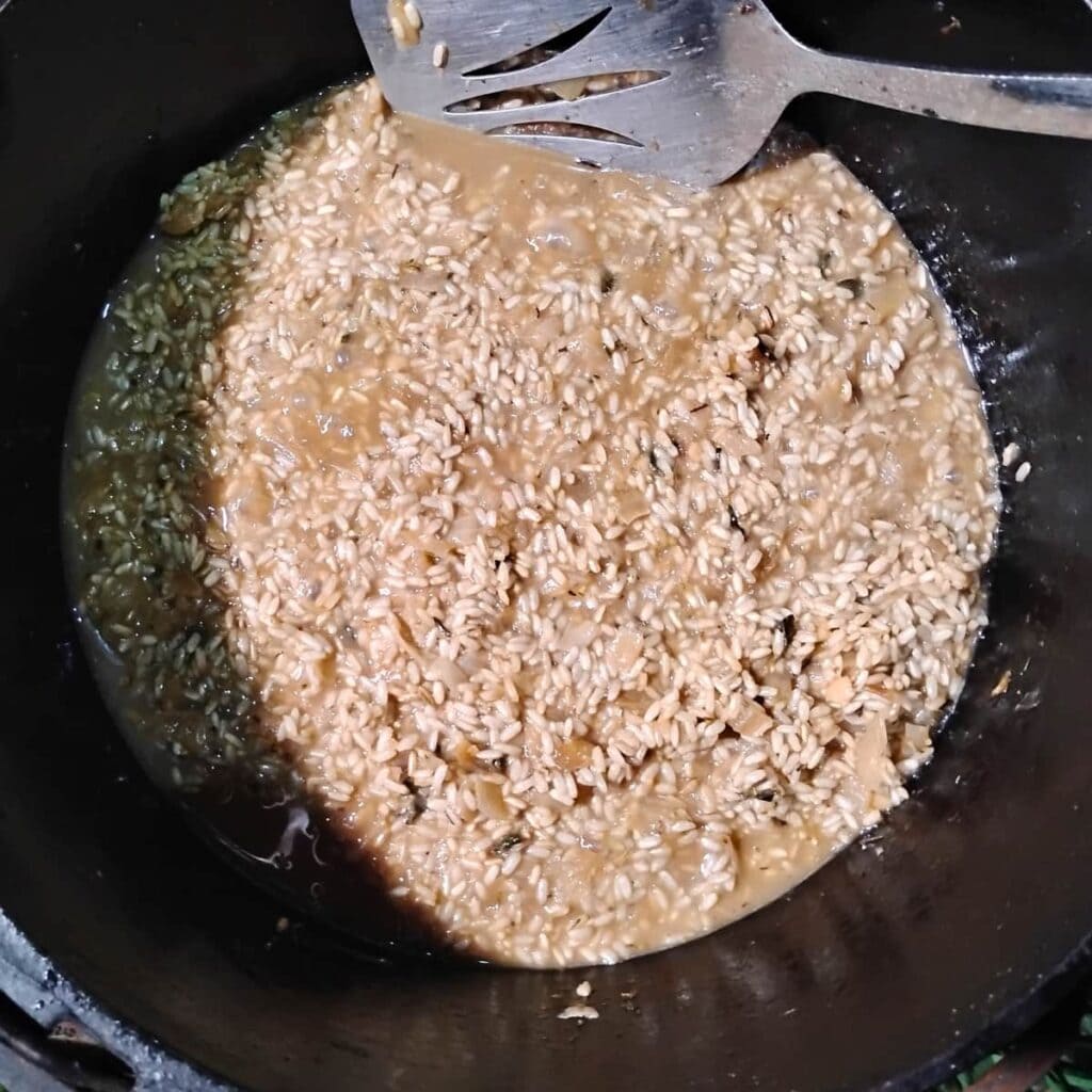 cooking mushroom risotto in a dutch oven with a small amount of broth added.