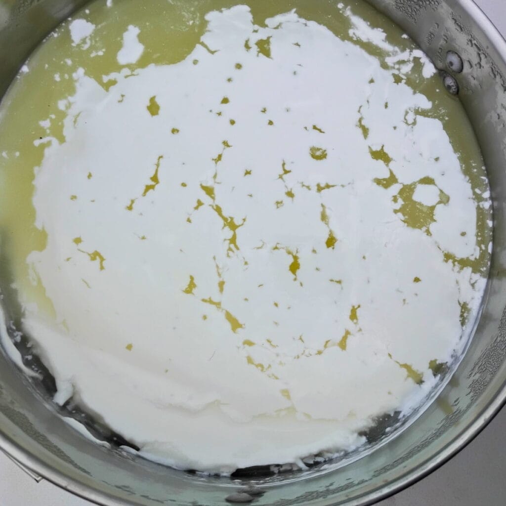 curds and whey have separated in a pot.