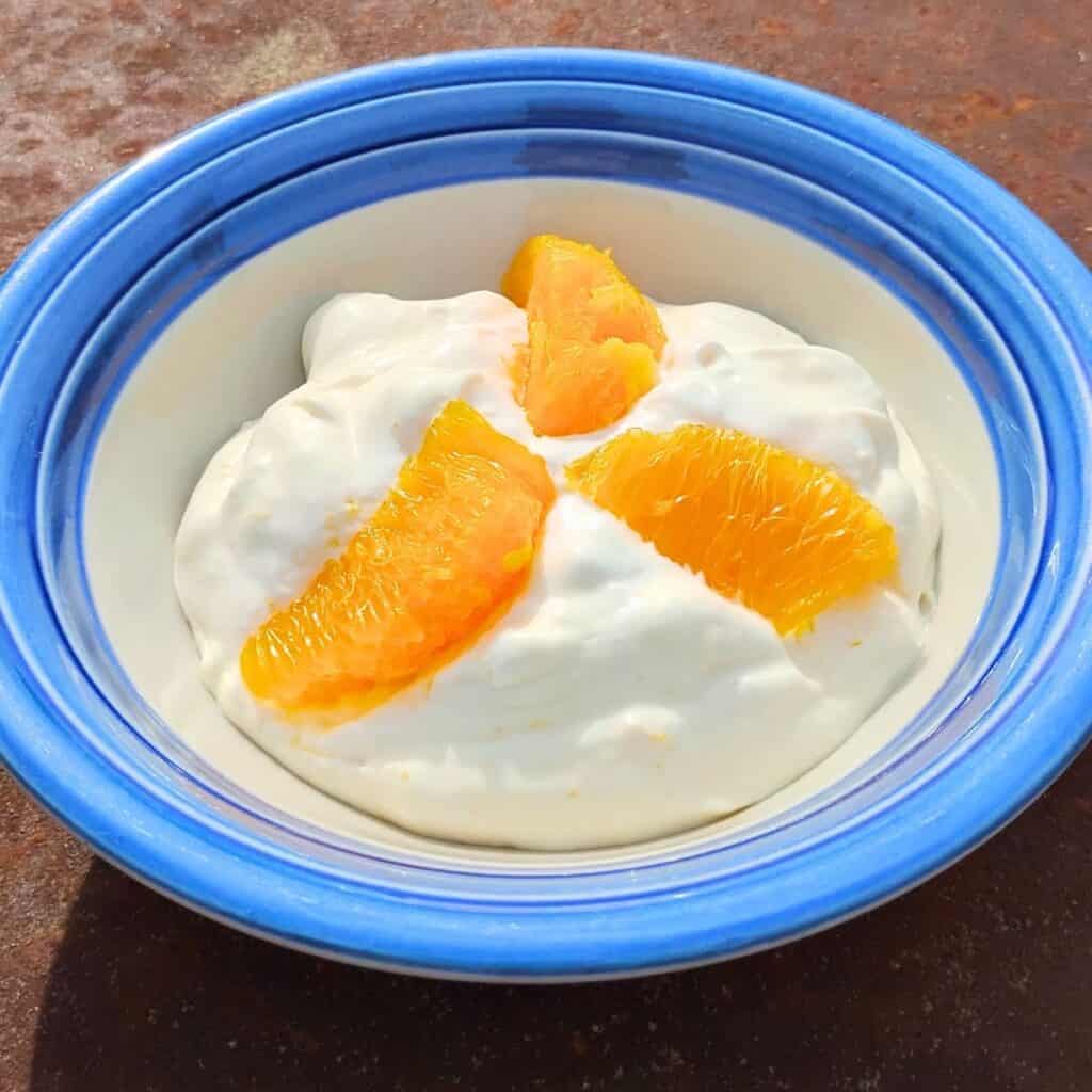 bowl with finished creamy quark cheese dessert and slices of an orange for decoration.