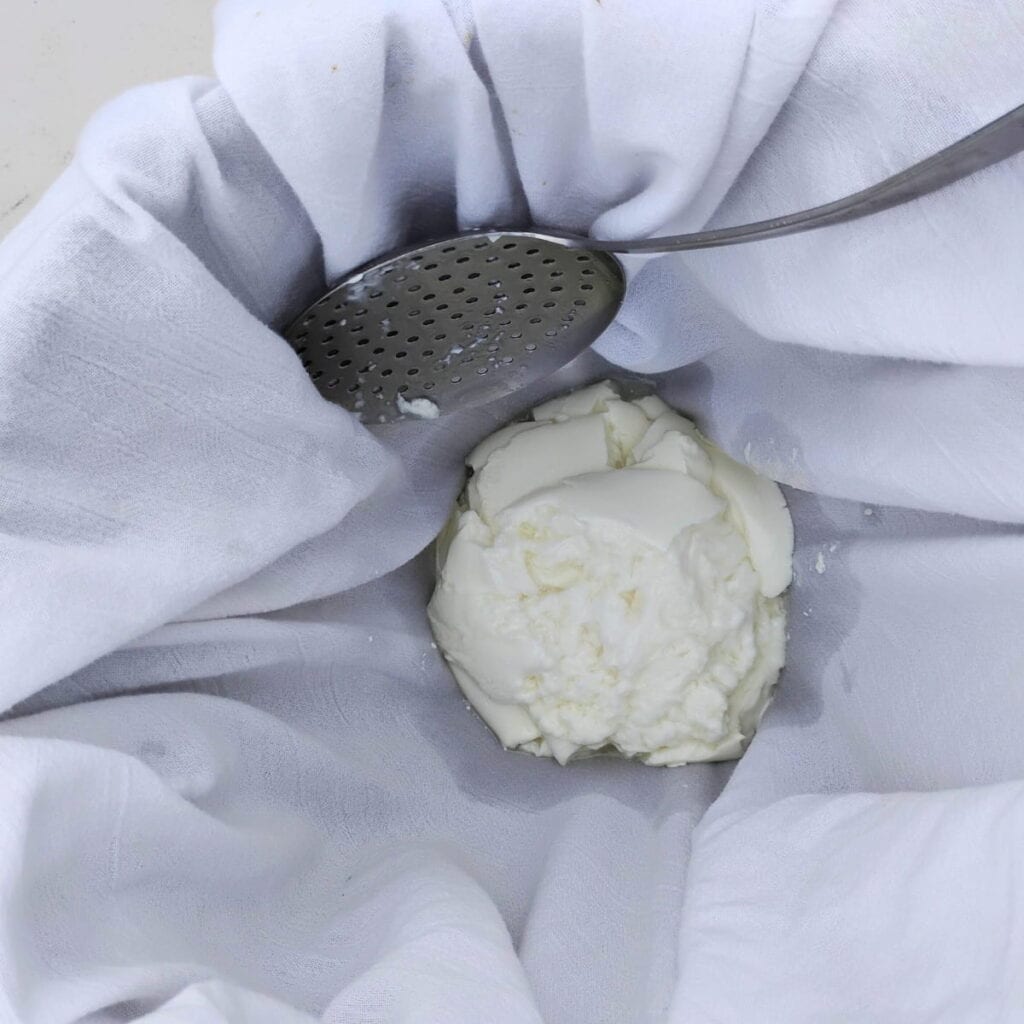 dropping the curds into the cheese cloth lined pot.