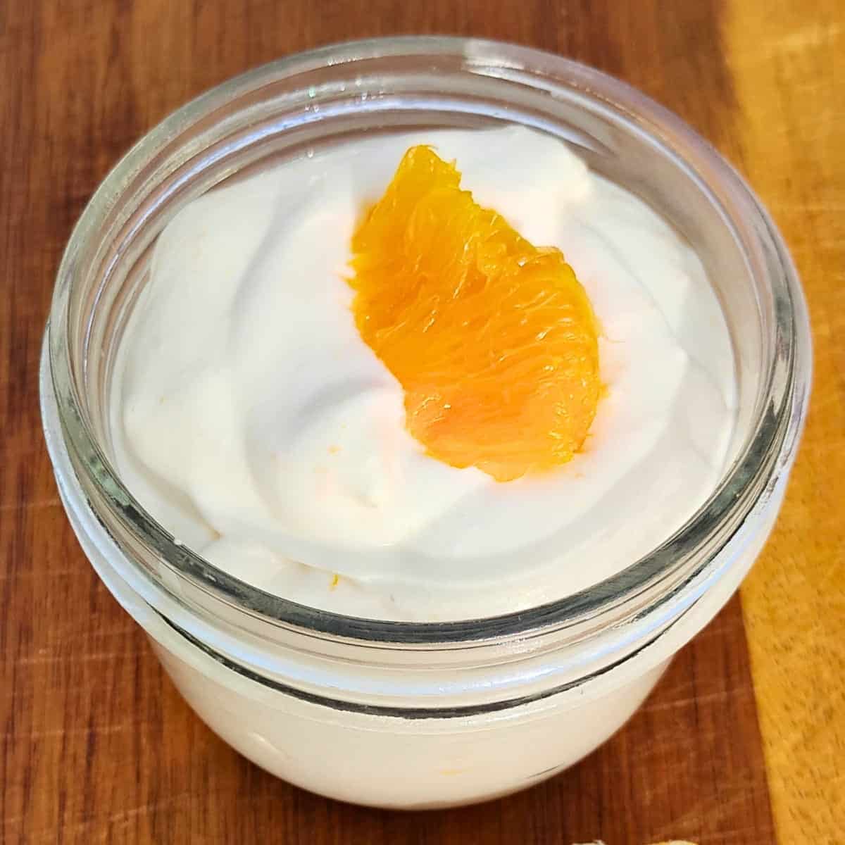 orange quark creme dessert in a small bowl, decorated with an orange filet slice.