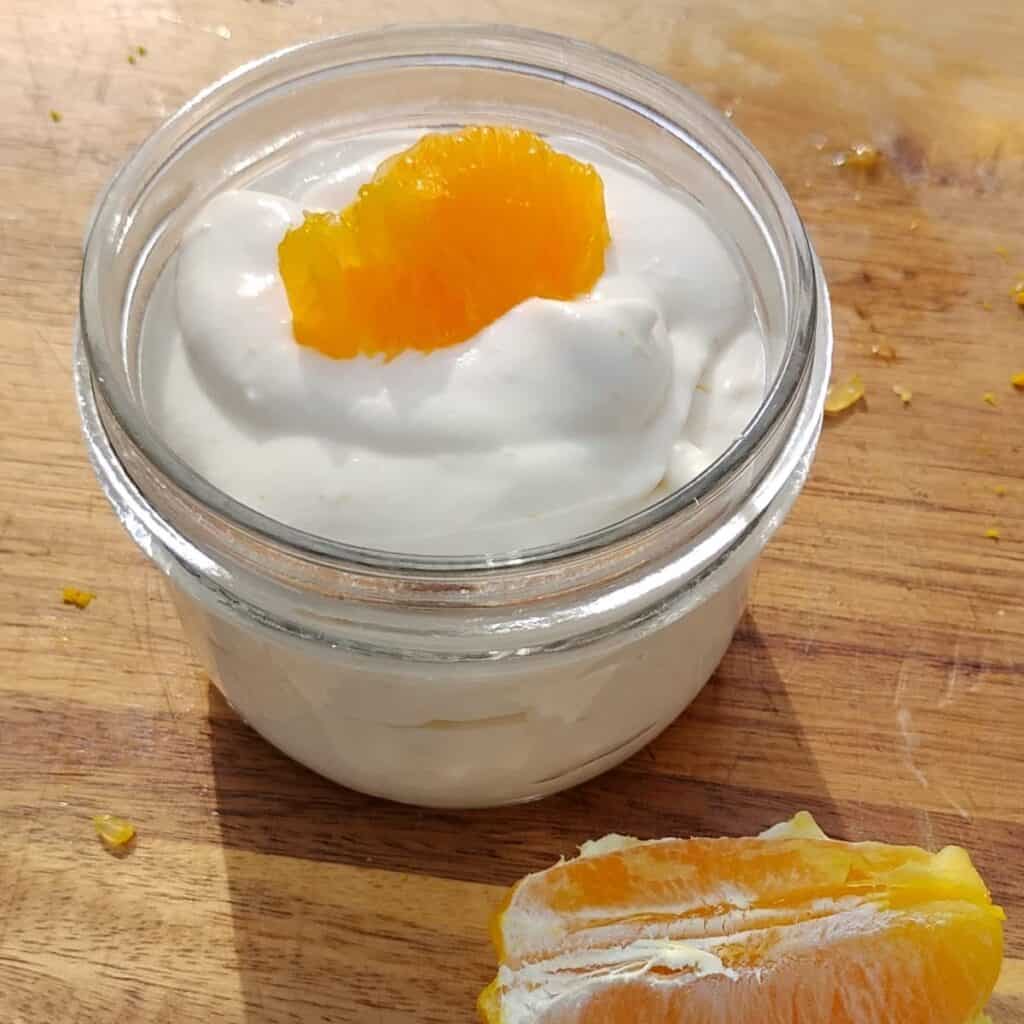 photo of orange quark creme in a bowl, decorated with a piece of orange.