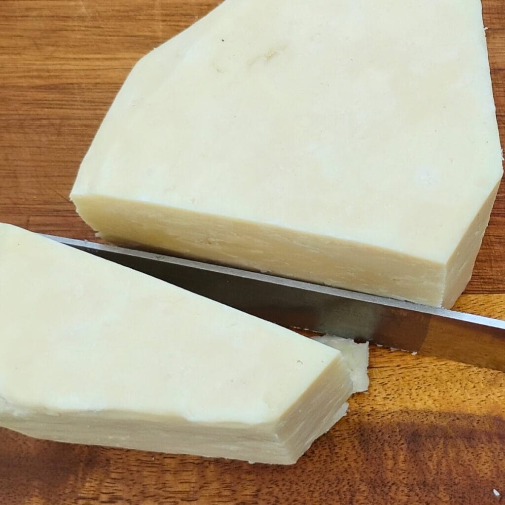 my 3-year old aged cheddar cheese that tastes like romano cheese. On a wooden board with a knife.