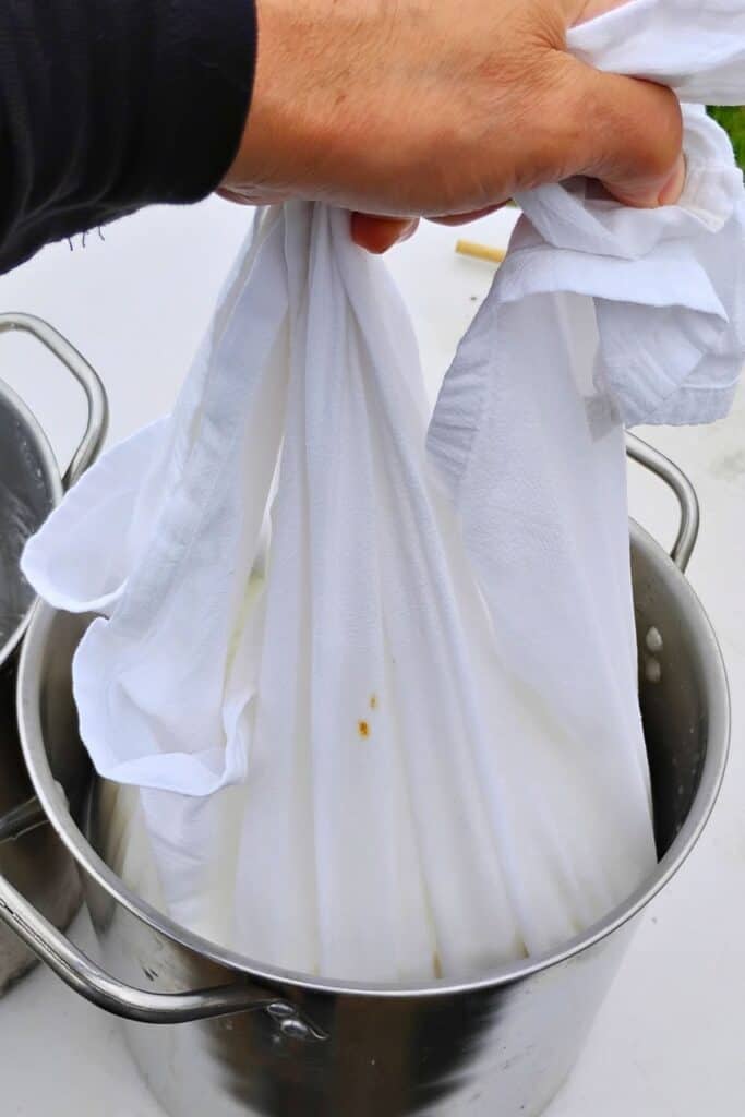cheese cloth in a person's hand filled with quark curds.