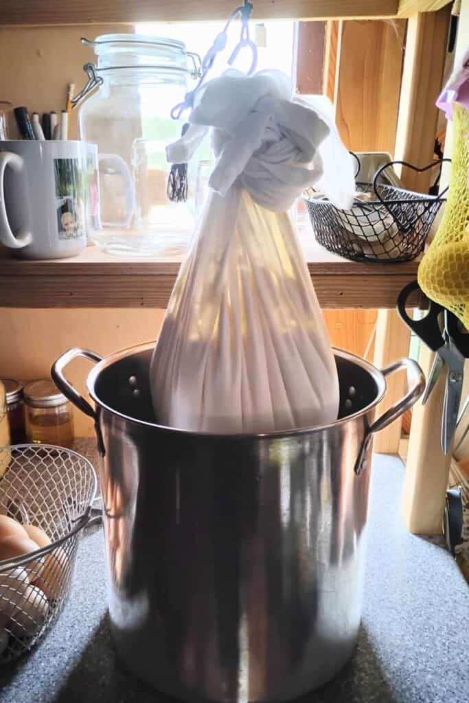 making quark cheese, curds in a bag hanging from a hook with a pot below it to catch the whey.
