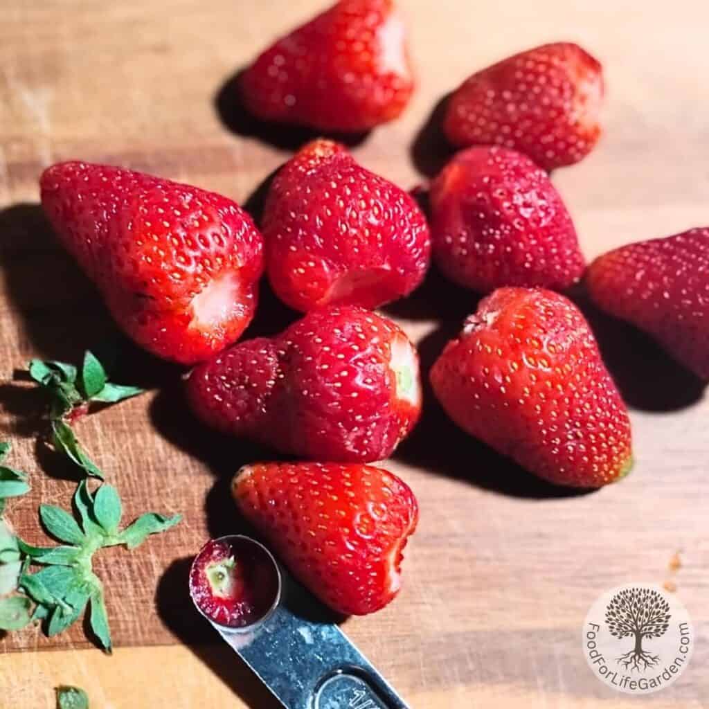 strawberries on a cutting board, getting prepared for making strawberry quark creme.