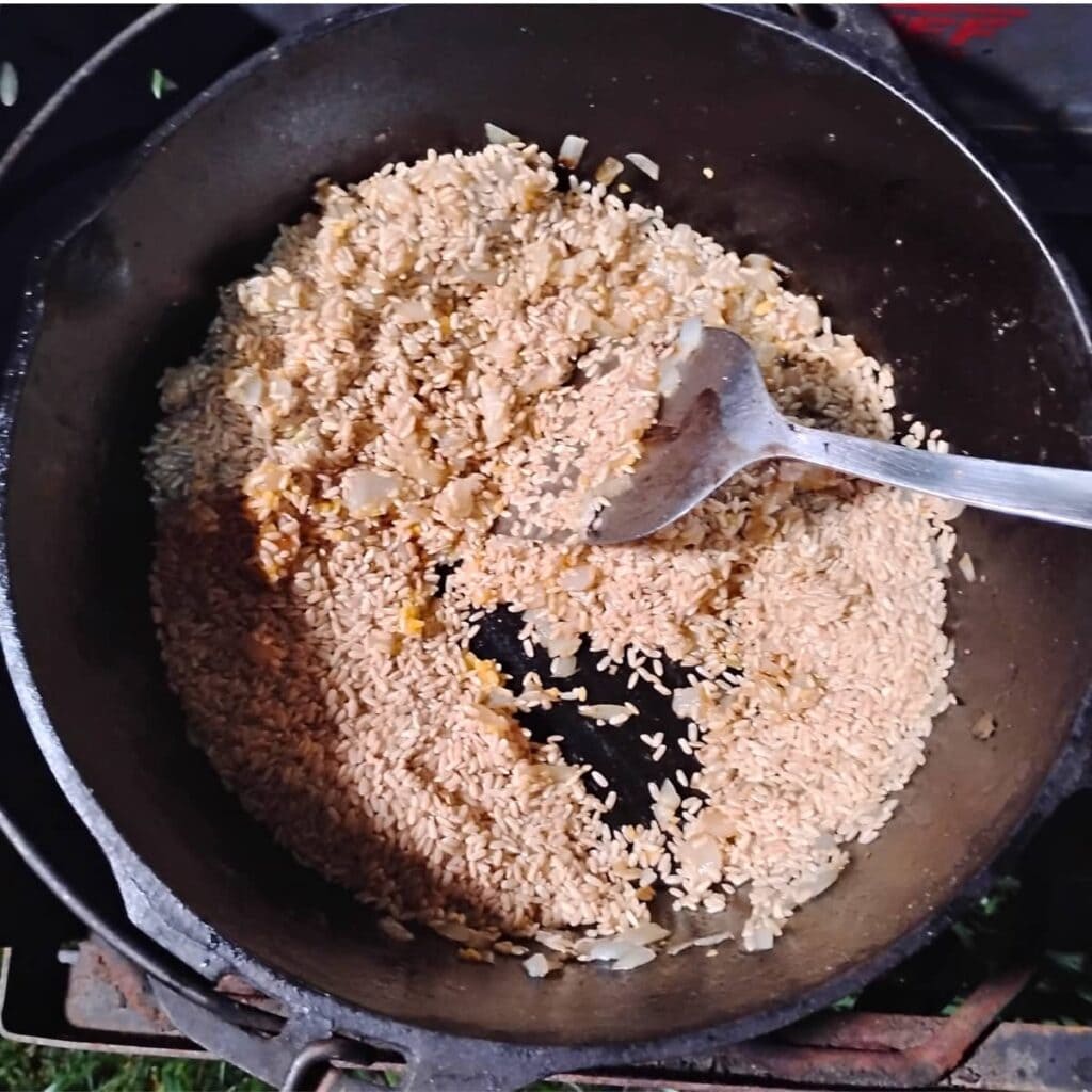 rice has been added to the onions and is getting toasted with some garlic too.