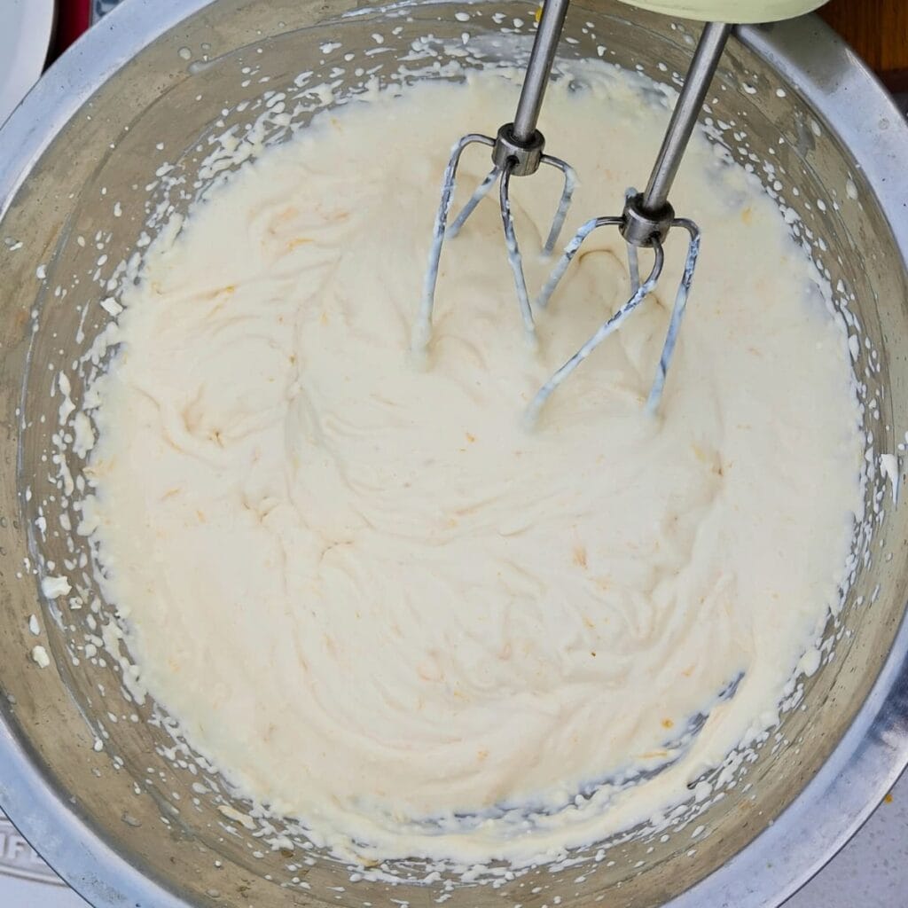 creamy sweetened cheese getting blended with ingredients.