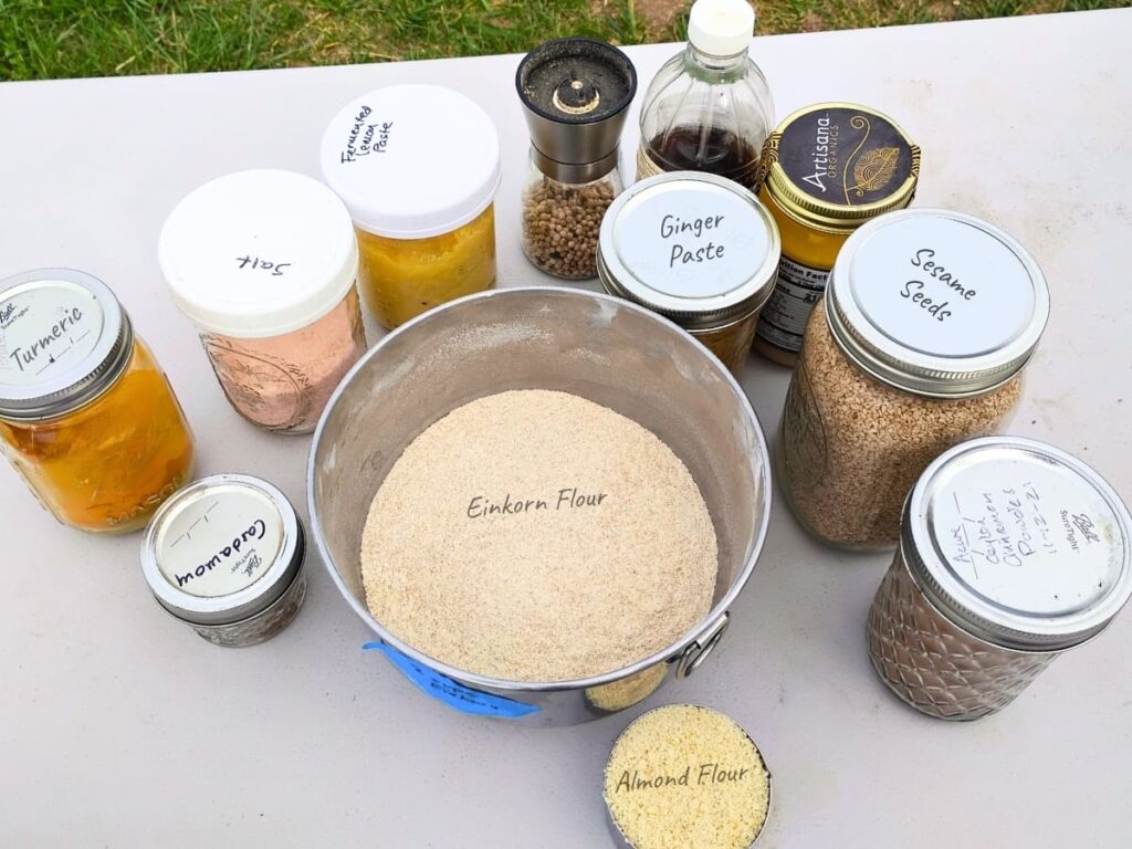 Ingredients for these honey tahini cookies. Turmeric, cardamom, sallt, fermented lemon paste, ginger paste, white pepper in a grinder, vanilla, ginger paste, sesame tahini, sesame seeds, Ceylon cinnamon, einkorn flour and almond flour.