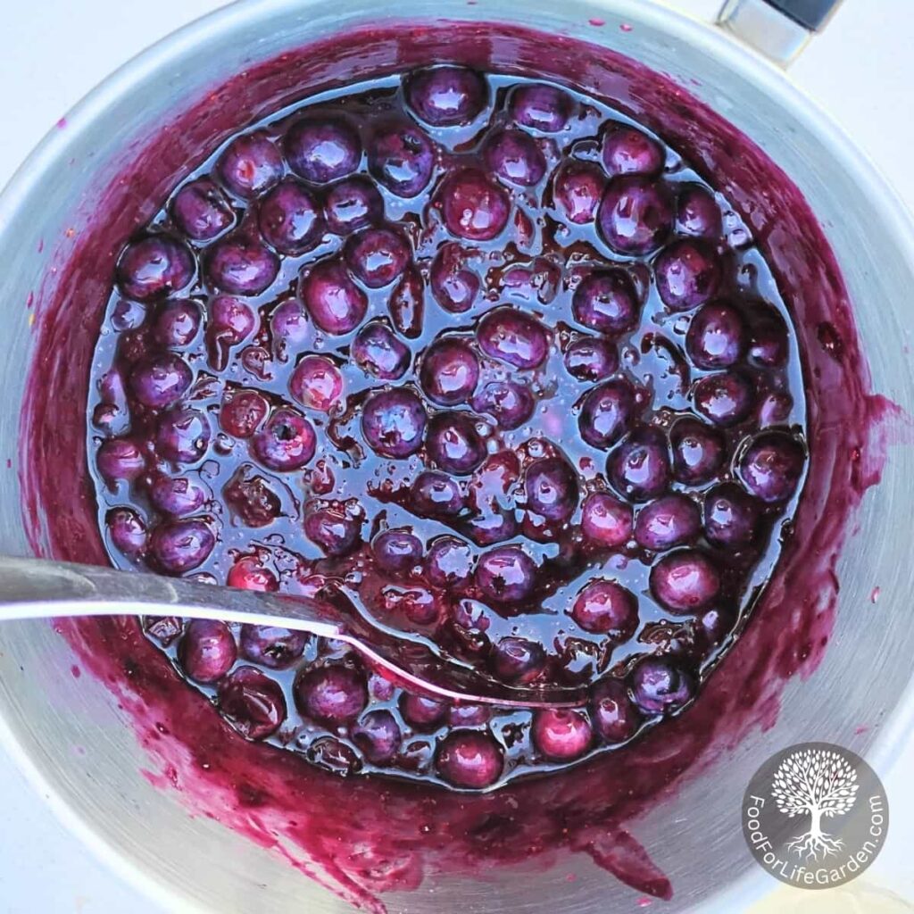 lemon blueberry sauce with fresh blueberries stirred in in a saucepan.