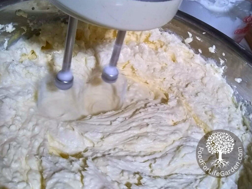 A hand mixer is mixing the sugar, flour and butter, eggs, quark and cream.