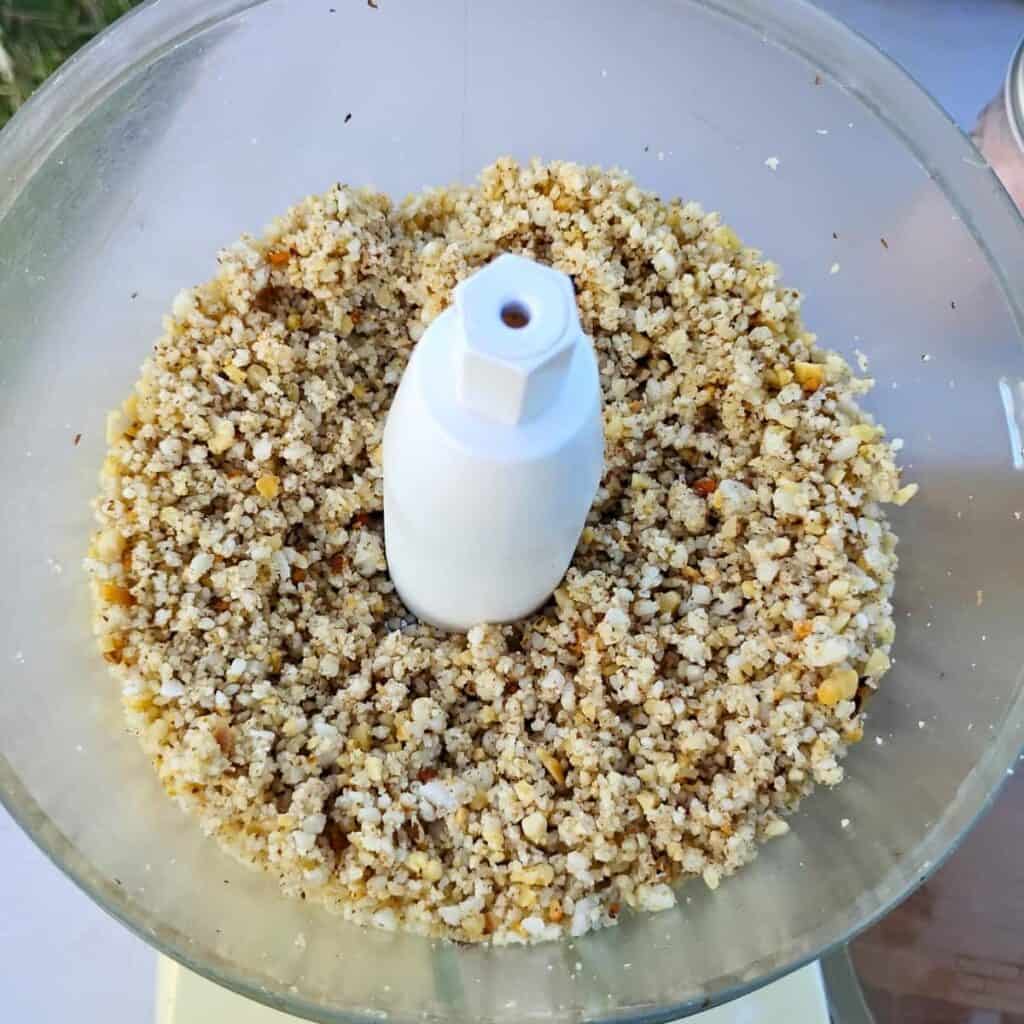 food processor bowl with chopped nuts and cheese