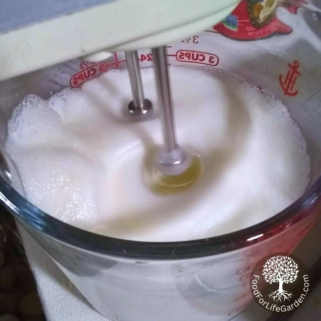 A hand mixer is beating egg whites into a stiff merangue.
