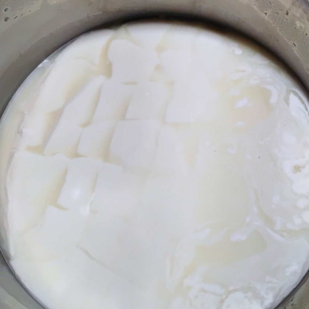 cheese curd that has been cut into a grid in a pot.