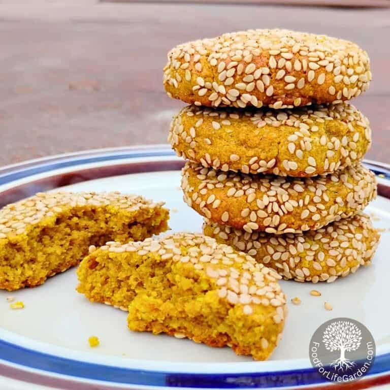 stack of spicy honey lemon tahini cookies with a broken cookie beside it on a plate.