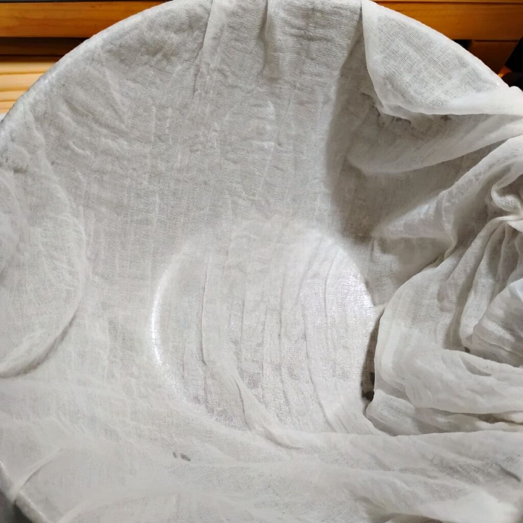 cheese cloth inside a bowl ready for getting filled with cheese curd cubes.