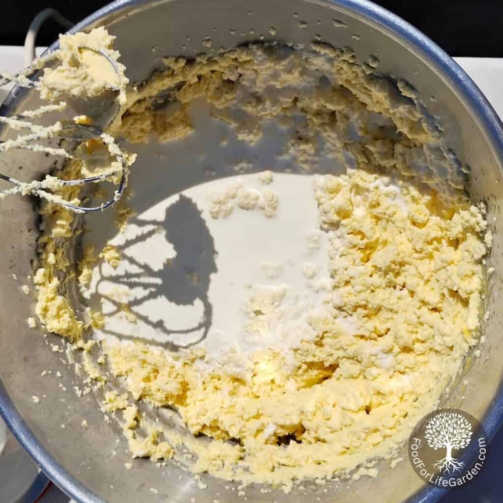 heavy cream is added to a bowl full of cheesecake batter.