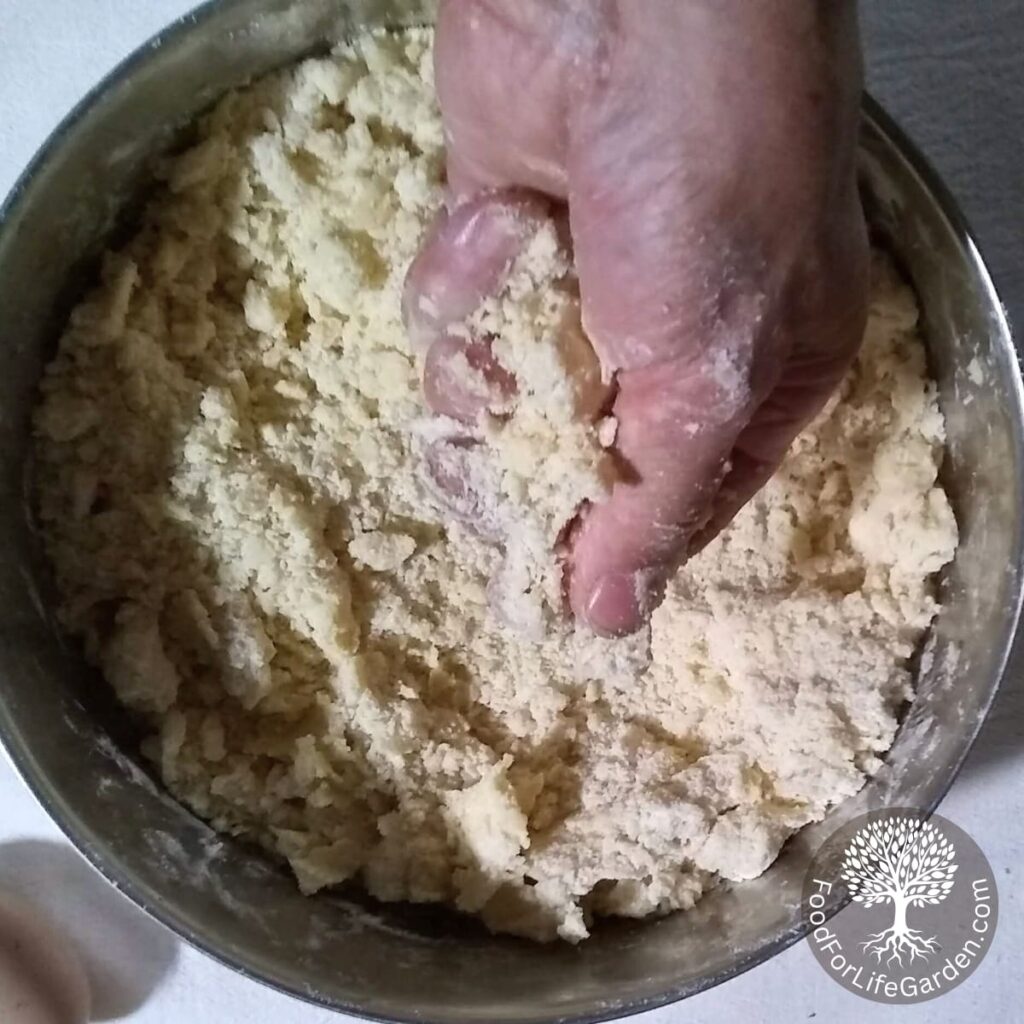 a hand making crumbles from flour, sugar, and butter.