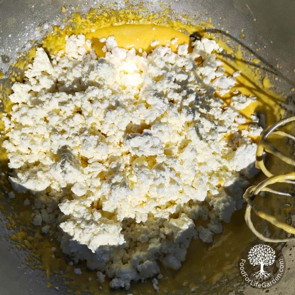 cheese is added to a bowl with batter.