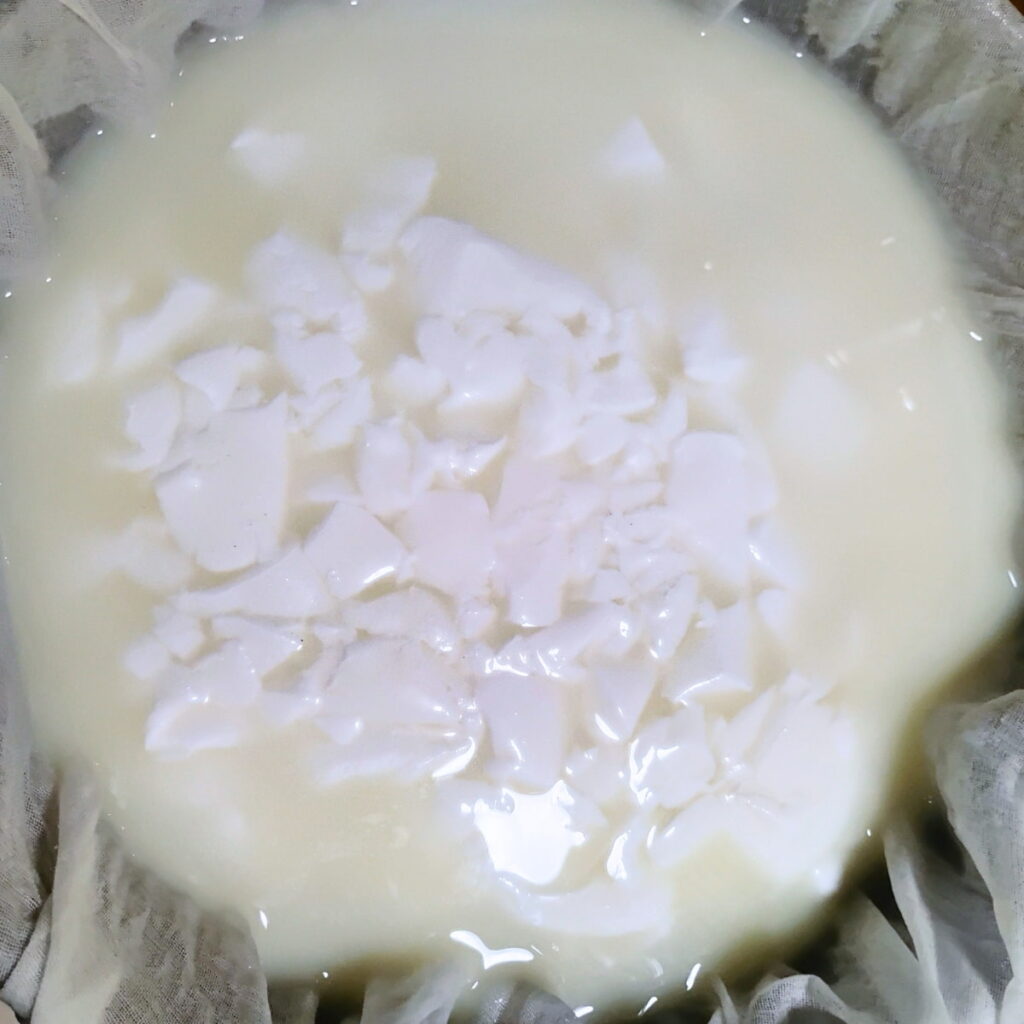 Cut cheese curd cubes inside a cheese cloth ready to be hung for draining.