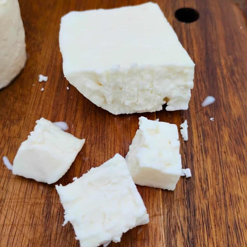 chunk and a few pieces of sirene cheese on a cutting board.