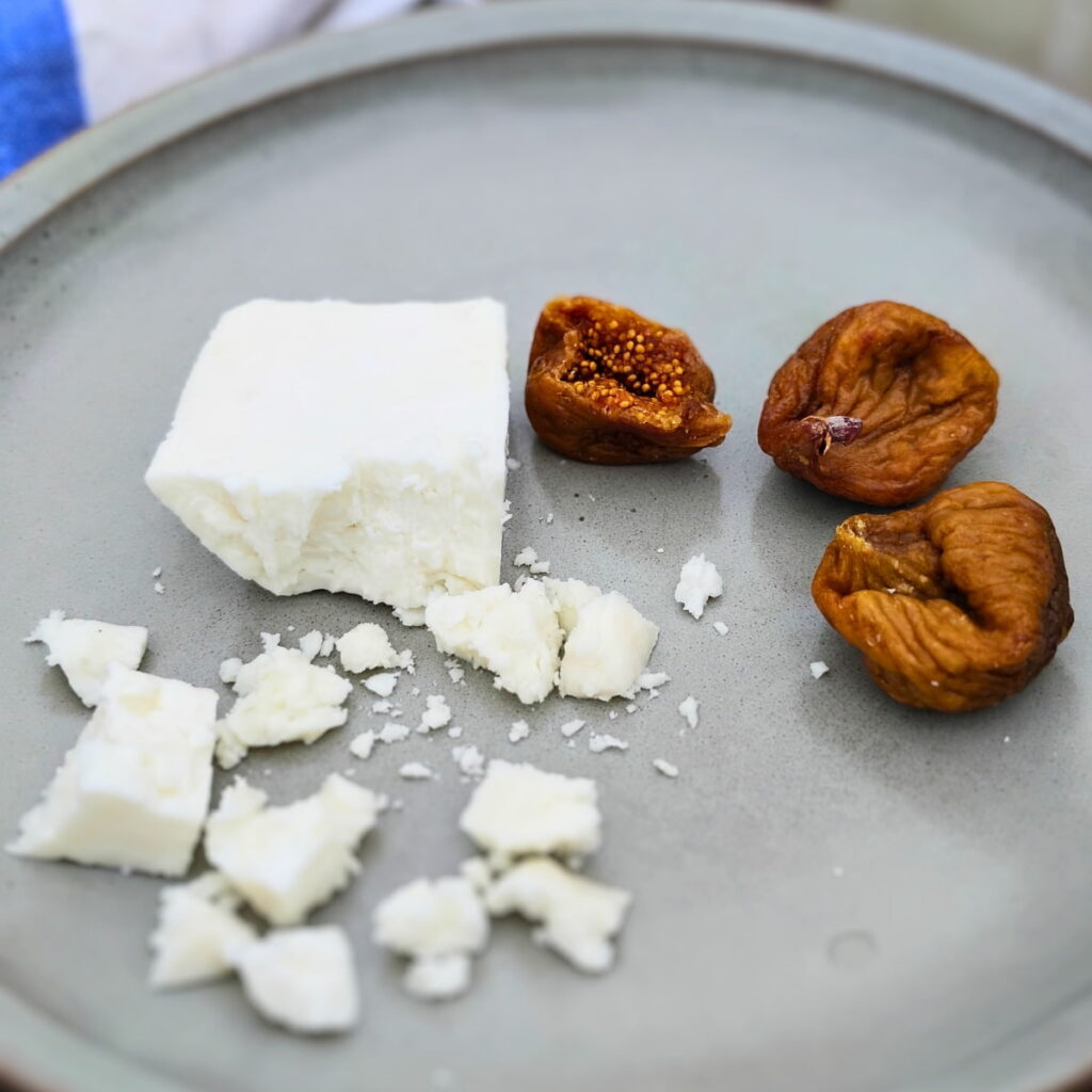 Plate with figs and a chunk of sirene cheese. A few more brocken and crumbled pieces of of this brine-aged white cheese.