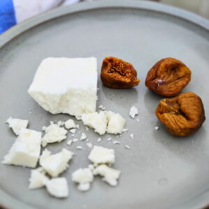 Plate with figs and a chunk of sirene cheese. A few more brocken and crumbled pieces of of this brine-aged white cheese.
