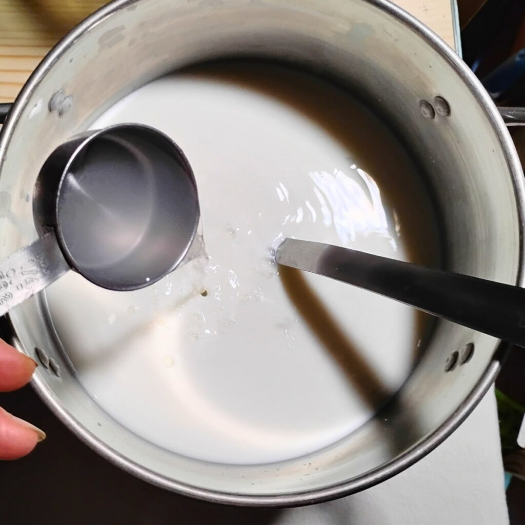 Adding rennet to the pot of milk