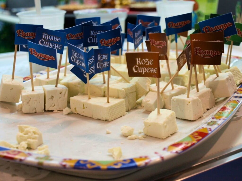 Display of bulgarian sirene cheese at a festival with small blue and red flags.