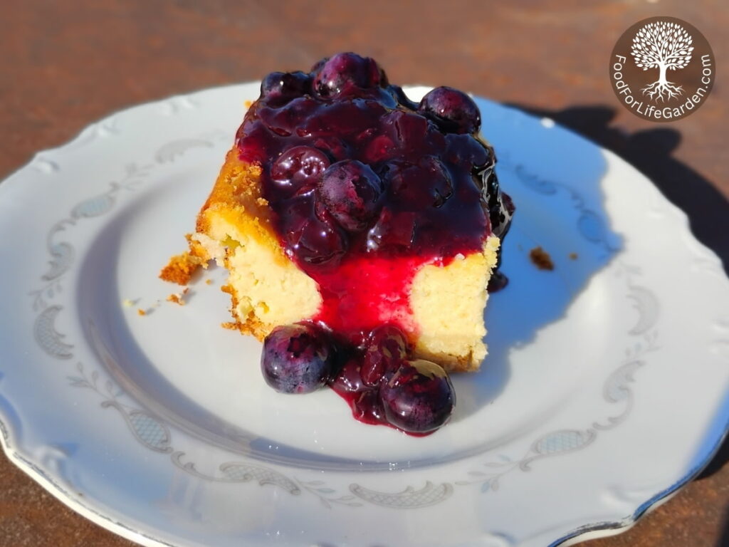 a slice of cheesecake with lemon blueberry sauce poured over it.