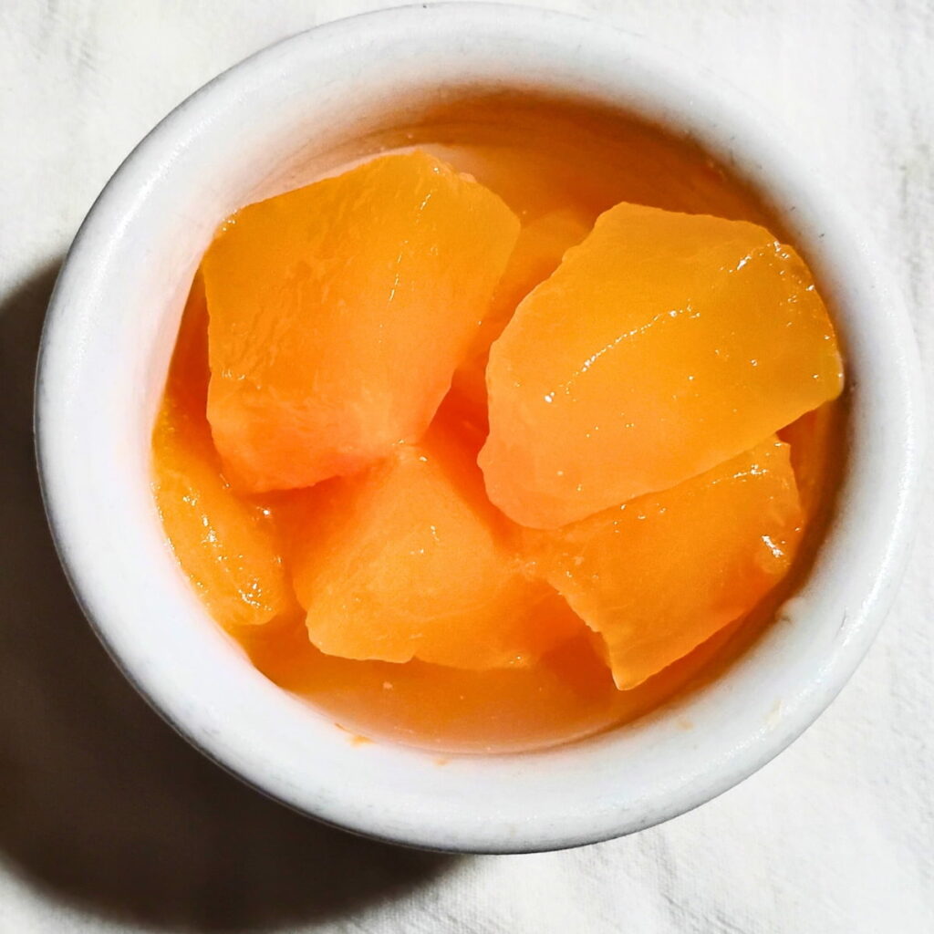 a small dish filled with fermented cantaloupe pieces and brine for eating. 
