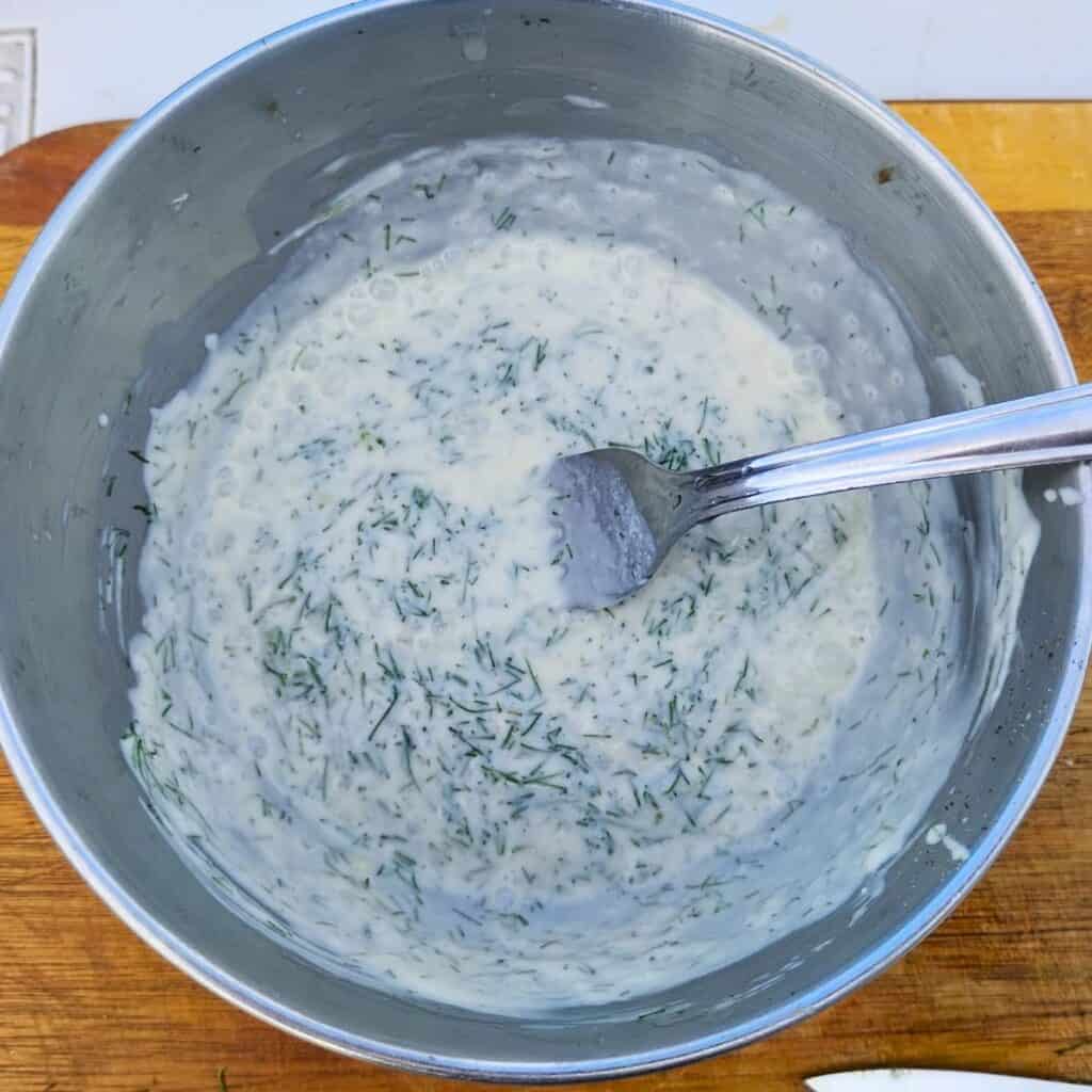 creamy salad dressing getting mixed up in a bowl.