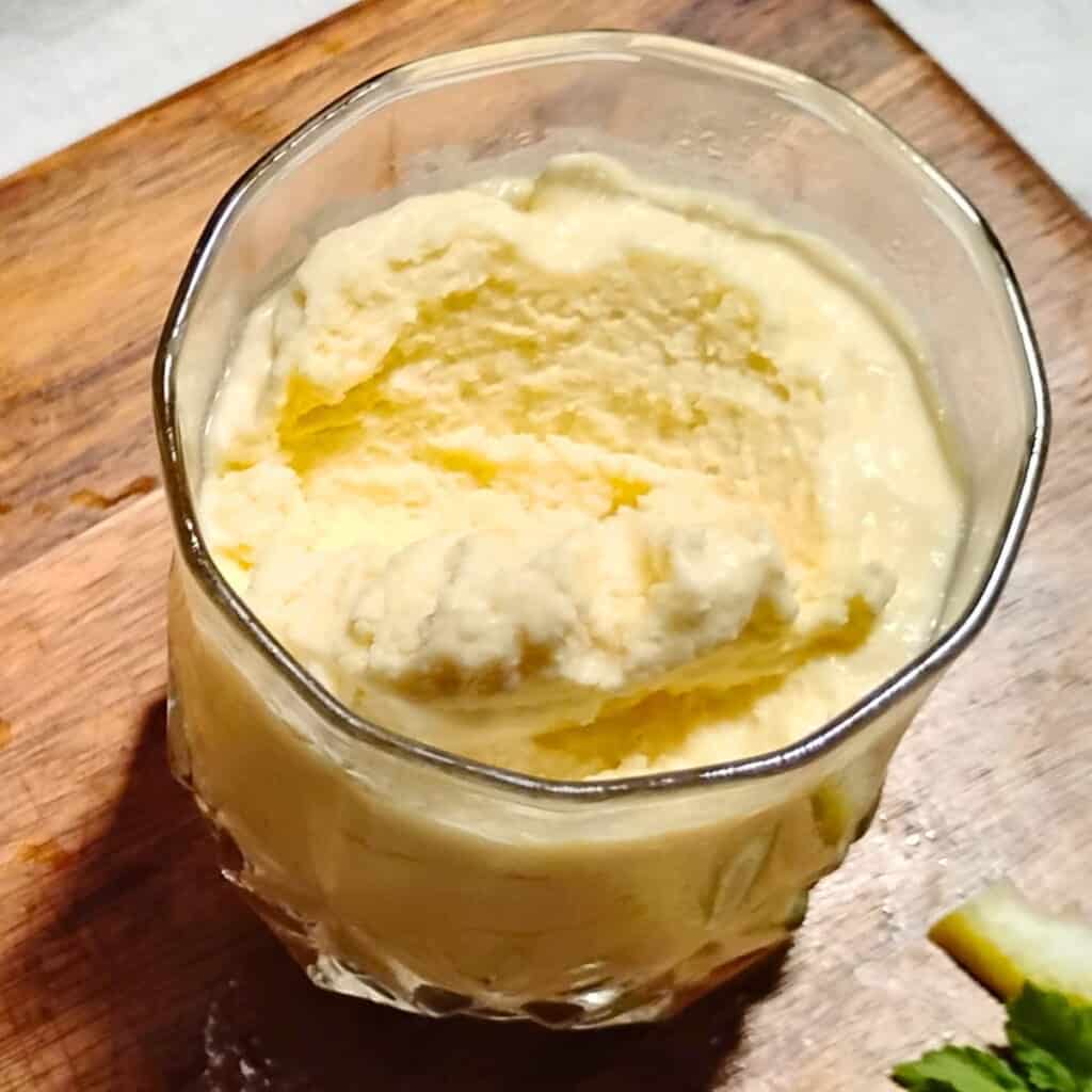 a glass filled with lemon cheesecake mousse that has been dipped into to show the texture.