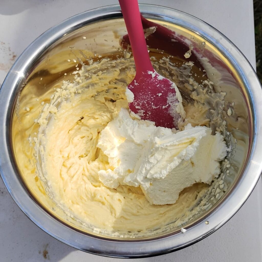 photo shows a bowl with a cheese batter, a silicone spatula and some whipped cream.
