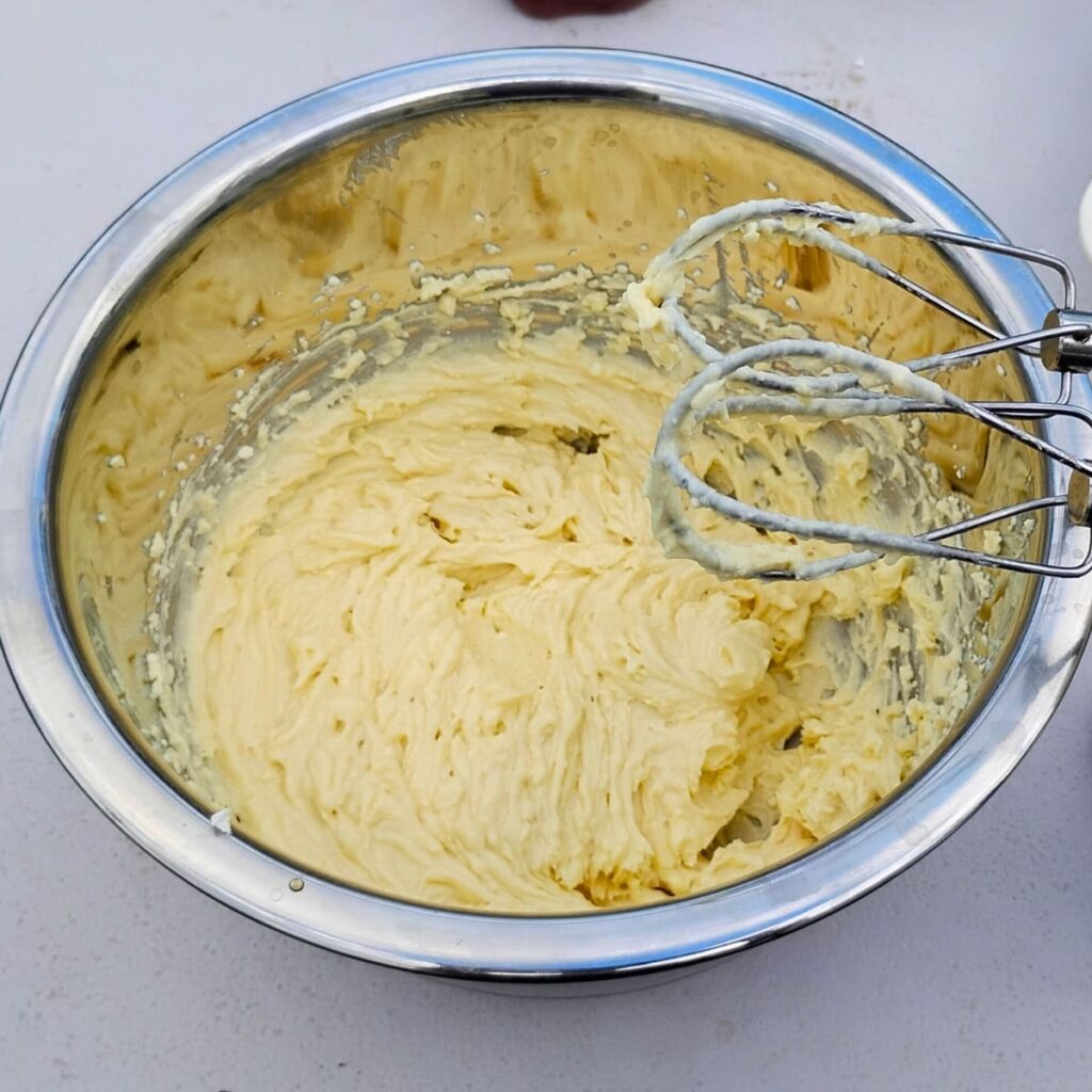 photo of a creamed cheese mixture in a bowl with beaters. 