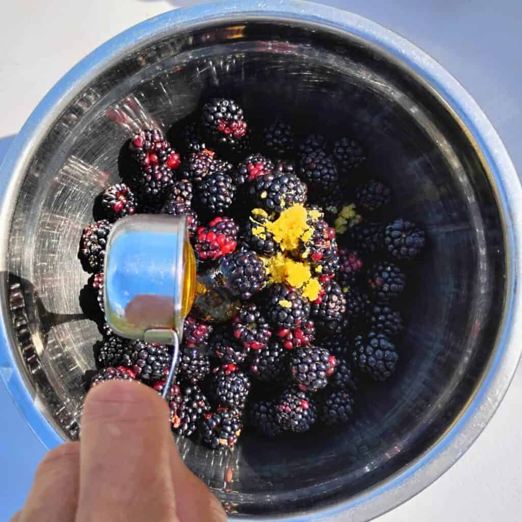 A bowl with blackberries and lemon zest. Honey is added to this. 