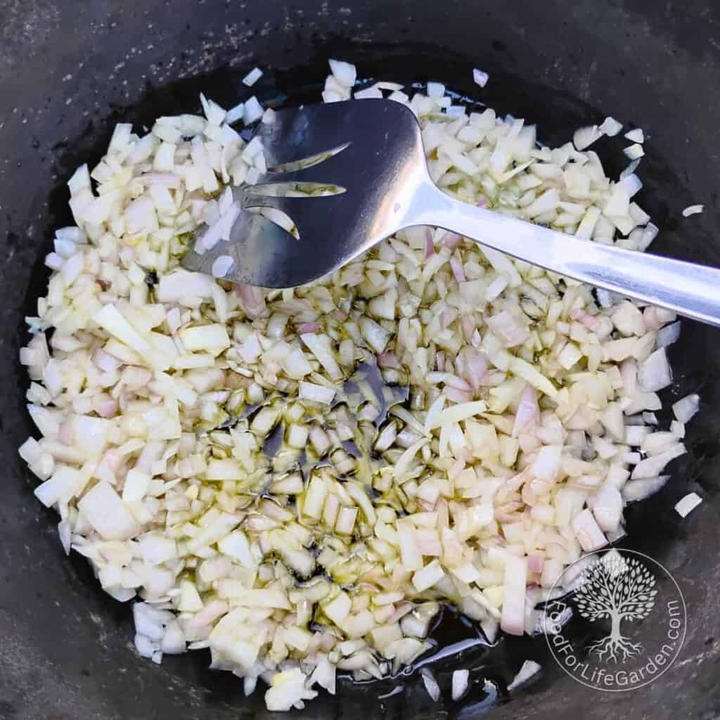 Dutch oven with onions getting sauteed in oil.