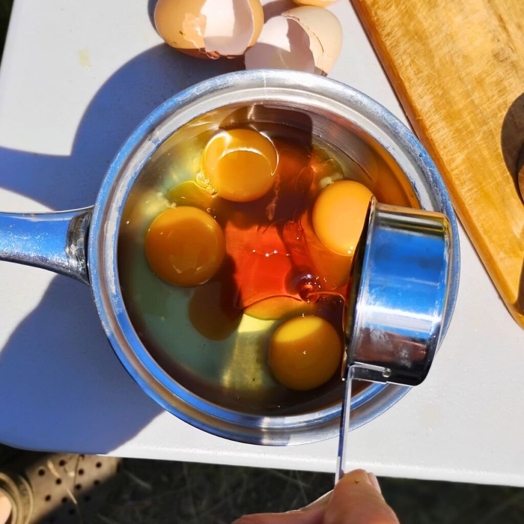 eggs and maple syrup are added to a pot for making lemon curd.