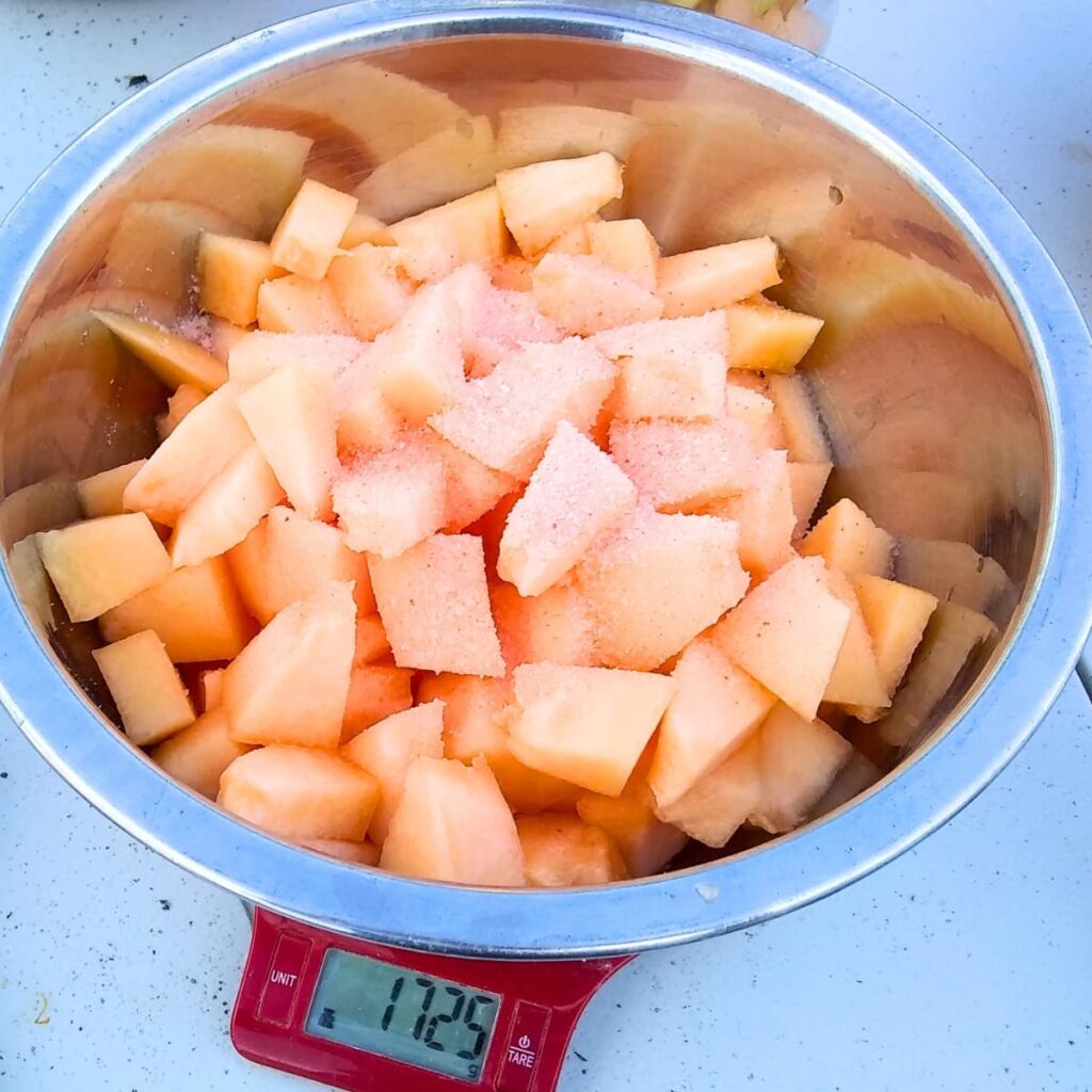 a bowl full of cantaloupe pieces on a scale with salt sprinkled on it. 