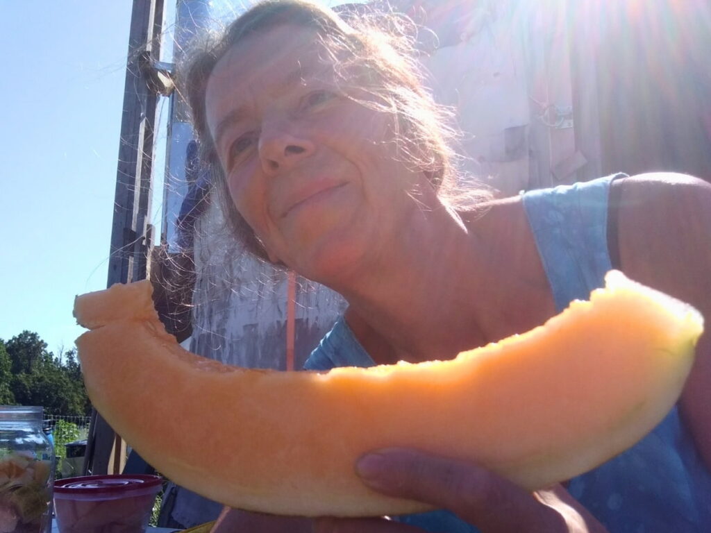 A person is holding up a humungous slice of melon. 